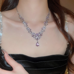 Close-up of elegant silver necklace with leaf-shaped purple crystal worn by a model