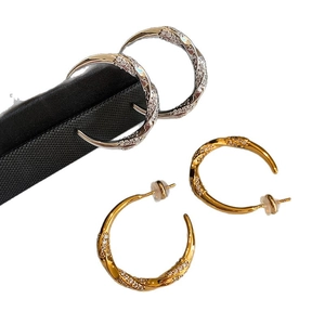 Gold and silver C-shaped twisted earrings with zircon stones on black silk background
