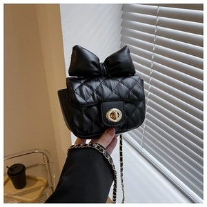 Close-up of black quilted mini bag with decorative bow and gold metal twist lock