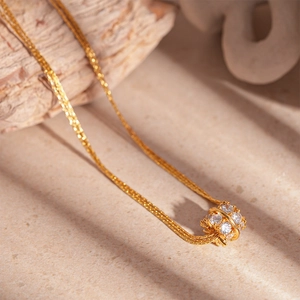 Dettaglio di una collana placcata oro con ciondolo a sfera tempestato di zirconi