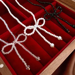 Bow pearl and crystal beaded necklaces in white, clear, and black on red velvet tray