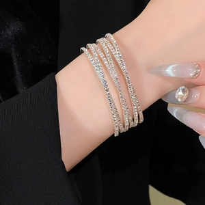 Detail van een sprankelende meerlaagse strass armband gedragen bij een zwart pak