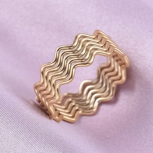 Macro shot of 18K gold plated wavy rings on purple satin highlighting wave textures