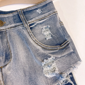 Dettaglio macro di pantaloncini di denim blu a vita alta con tasche ed effetto strappo