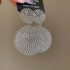 Close-up detail of silver hollow mesh circular drop earrings with fine metallic texture