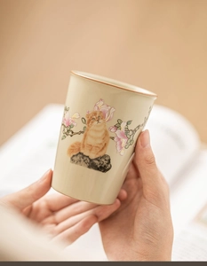 Close-up of a Ru-kiln ceramic teacup featuring an orange cat and pink floral design