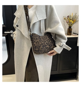 Chic brown leopard print crescent bag styled with a neutral coat in a modern setting