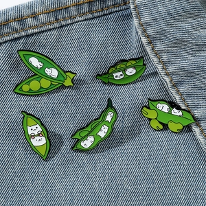 Set of five creative cat in pea pod enamel pins displayed on blue denim fabric