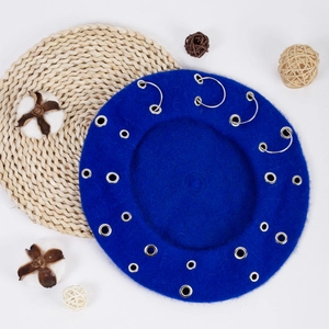 Close-up of blue wool beret featuring silver metal rings on woven placemat decor