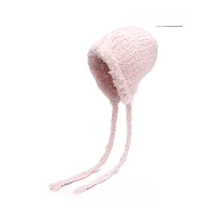 Detailed texture of light pink plush knit hat featuring soft faux fur and long chin straps