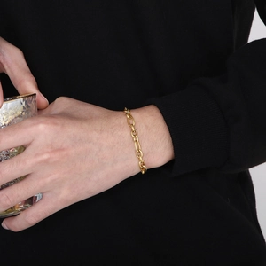 Vintage 6mm gold stainless steel O-link chain bracelet worn by a model on a dark background