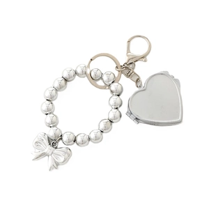 Silver plated bead keychain with bow and heart locket charms on white background