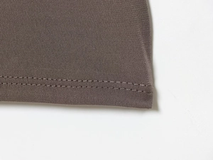 Detailed close-up of double-needle hem stitching on a brown V-neck mini dress
