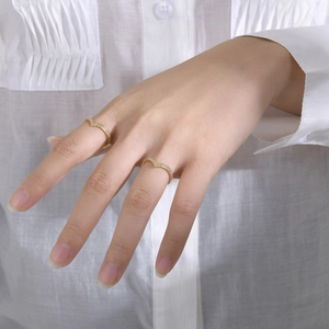 Detailed view of two V-shaped gold rings with pave-set cubic zirconia on a model hand
