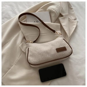 Detailed texture of woven fabric and brown leather trim on a vintage underarm bag