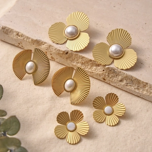 Boucles d'oreilles fleuries dorées chic avec perles sur texture de pierre minimaliste