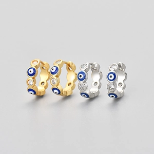 Golden and silver evil eye huggie hoop earrings with blue enamel and zircon stones