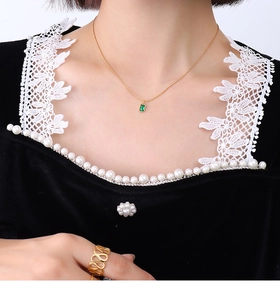 Close-up of gold necklace with emerald pendant and hollow ring on elegant model