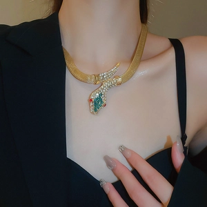 Detailed view of vintage gold snake necklace with sparkling green and red rhinestones