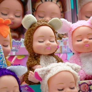 Detail of plush animal-themed sleeping baby dolls with various colorful costumes