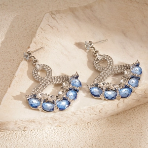 Retro fan-shaped drop earrings with blue and white crystals on a stone surface