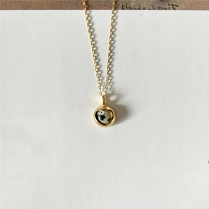Macro view of gold-plated heart pendant with black and white spotted dalmatian jasper stone