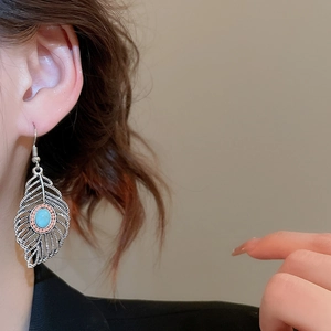 Detailed view of vintage leaf earrings with oval turquoise and pink bead accents on model