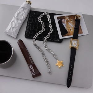 Detailed view of silver chain necklace with a gold star pendant on a gray background