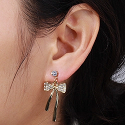 Close-up of elegant gold bow earrings with shimmering zircons worn by a model