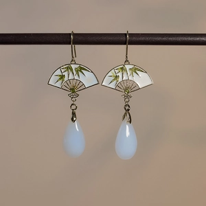 Detail von eleganten Fächerohrringen mit grünen Bambusblättern und weißen Tropfenperlen