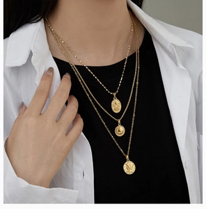 Close-up of layered 18K gold plated titanium steel necklace with coin and angel pendants