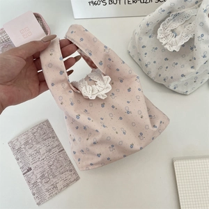 Dettaglio della borsa in tela floreale con raffinato bordo in pizzo e piccoli fiori blu