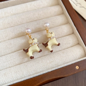 Detail of creative puppy enamel earrings with pearls and gold accents on velvet tray