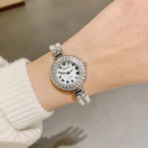 Detail of luxury pearl bracelet watch with diamond bezel and white mother-of-pearl dial