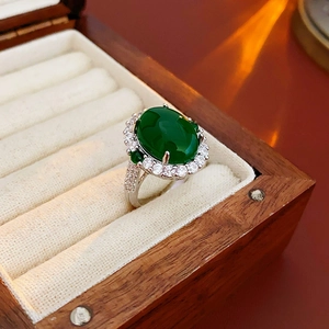 Macro view of vintage silver ring with oval emerald zircon and pave diamonds on wood box