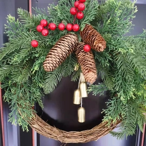 Close-up of Christmas wreath with evergreen branches, pine cones, and gold bells.