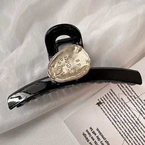 Glossy black shark hair claw with textured silver metal plate and numeric engraving