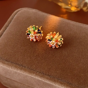 Macro detail of gold flower earrings with colorful zircon stones on brown velvet box