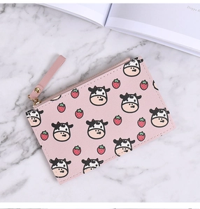 Detailed close-up of a pink small coin purse with cartoon cow and strawberry patterns