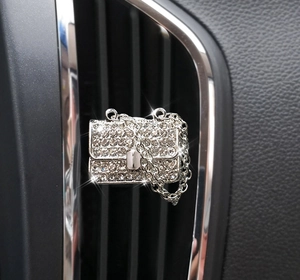 Macro shot of silver diamond-encrusted handbag car air vent perfume clip with metal chain