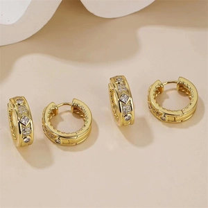Détail de boucles d'oreilles créoles dorées avec zircons carrés et ronds étincelants