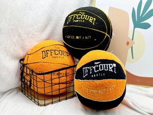 Detailed close-up of three plush basketball pillows with embroidered sports typography