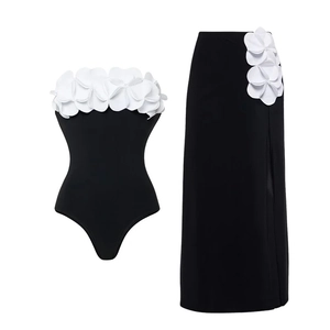 Detail of 3D white floral applique on black strapless swimsuit and high slit skirt