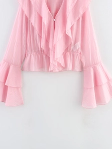 Détail du chemisier en mousseline rose avec volants au col en V et manches évasées