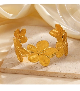 Dettaglio di bracciale rigido floreale dorato con petali testurizzati su pietra