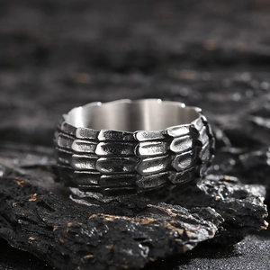 Macro detail of silver dragon scale texture on punk ring set atop dark textured stone