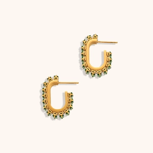 Détail de boucles d'oreilles dorées en C avec pierres de zircon vert émeraude