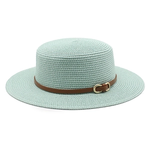 Détail d'un chapeau de paille vert menthe avec bande en cuir marron et boucle dorée