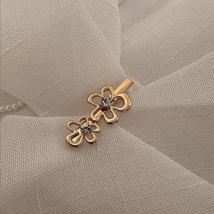 Détail d'une barrette dorée avec motif de double fleur et centres en zircon