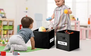 Macro detail of foldable black fabric bins with handles and Kate's Toy label in a kids room